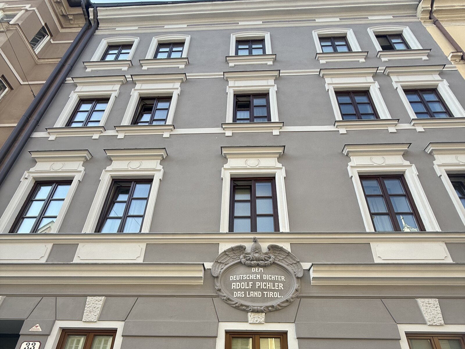 Gründerzeitfassade in Innsbruck, grau verputzt, mit Sprossenfenstern