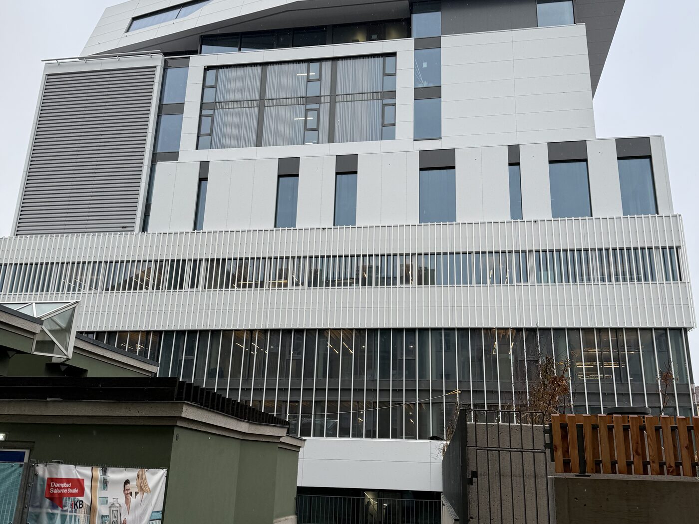 Mehrgeschossiger Neubau mit Fassade in Fertigstellung, von der Straße aus gesehen