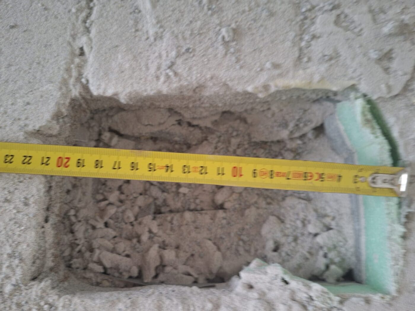 Geöffnete Wand mit freigelegtem Mauerwerk, daneben ein angelegtes Maßband