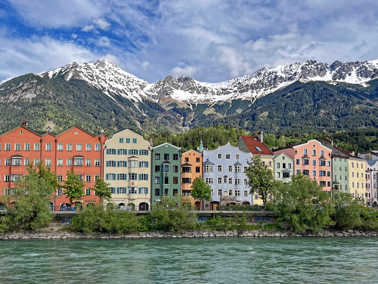 Die bunte Häuserzeile der Mariahilfstraße am Inn in Innsbruck, dahinter die verschneite Nordkette