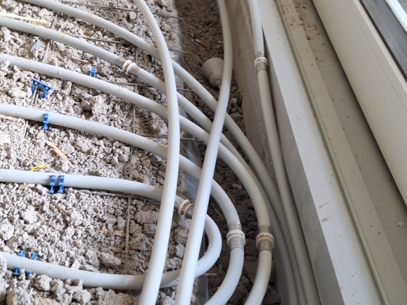 Weiße Kunststoffrohre und Kabel, in einer offenen Wand verlegt